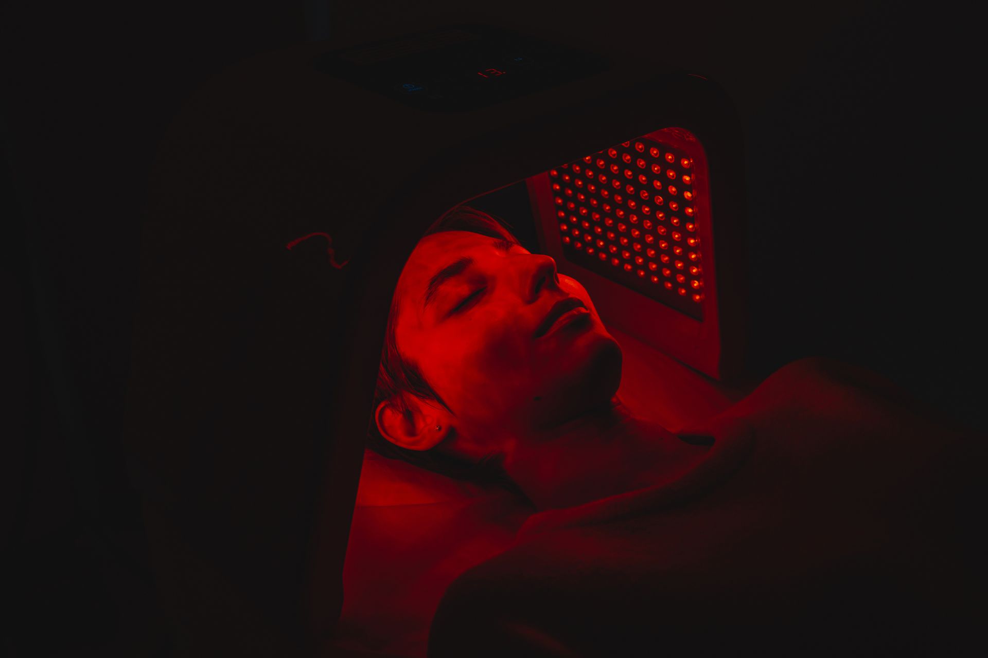 Small red light therapy room with warm LED glow and espresso wood floor.